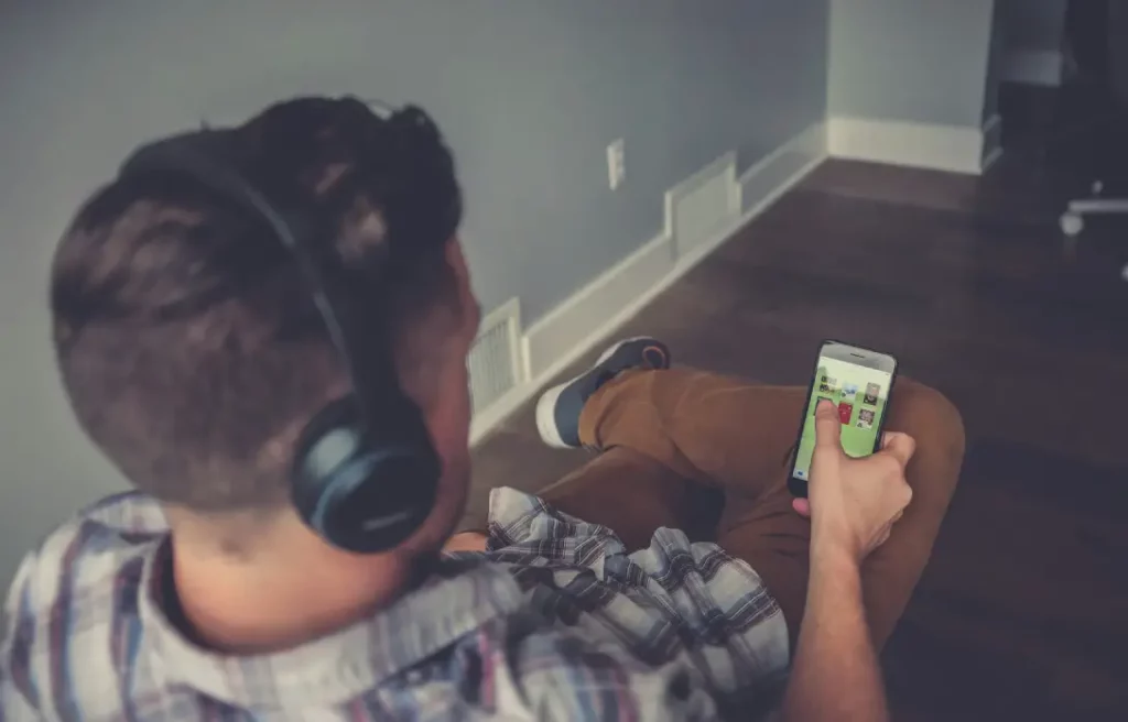 Person listening to an audiobook on headphones with an open book nearby