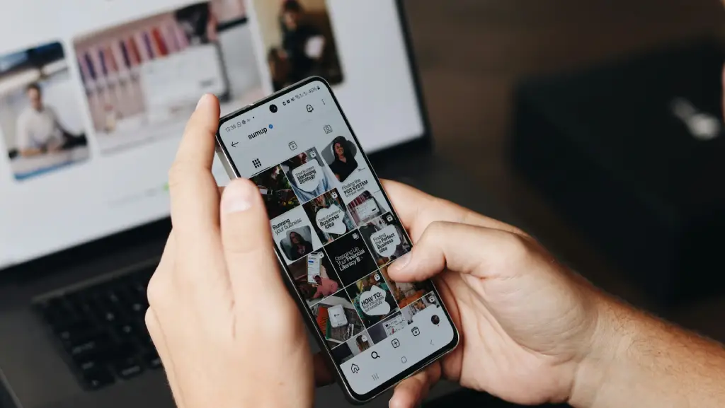 Person using Instagram content creation services tools on mobile with content calendar on laptop