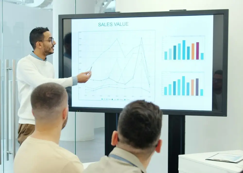 Analyst walking colleagues through a data-dense chart, typical of IB pitch deck design