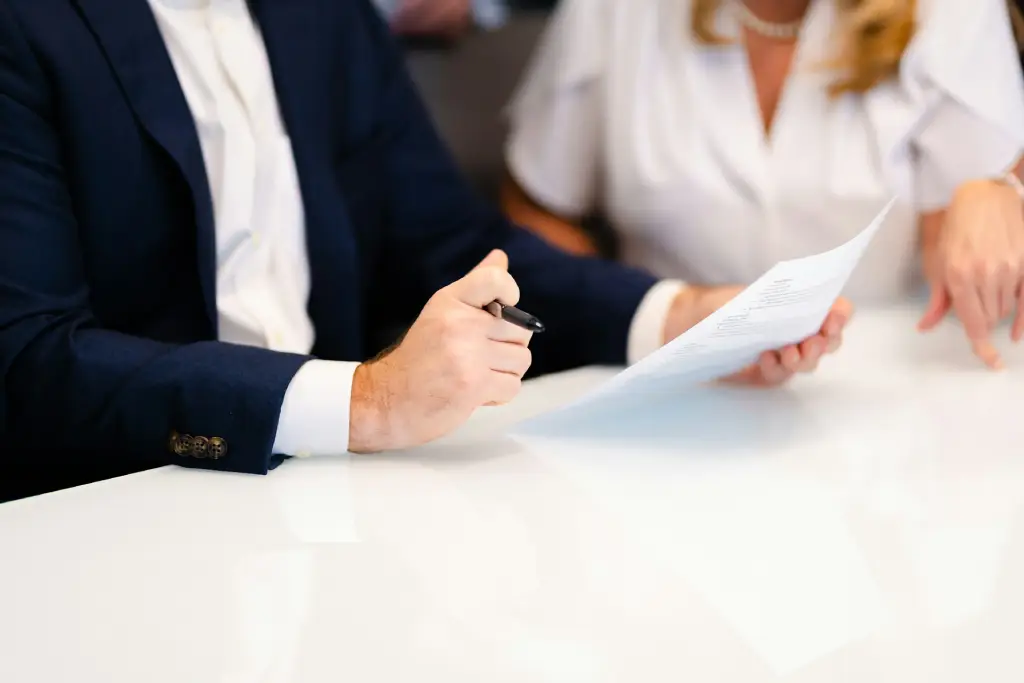 Executive reviewing a printed business proposal with a colleague at a white conference table