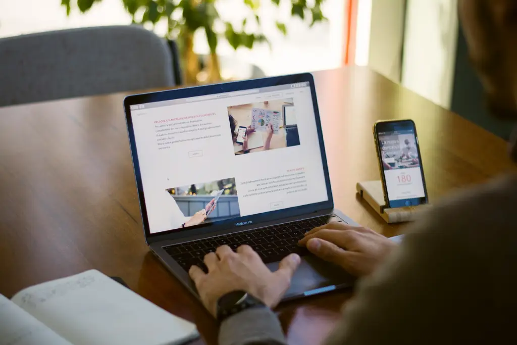 Writing website content on a laptop with a phone nearby